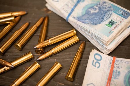 Scattered rifle cartridges lying next to a file of banknotes.の写真素材