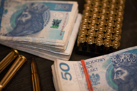 Rifle and pistol ammunition lie on the table along with banknotes.の写真素材