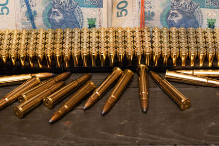 Lined up ammunition on a gun case along with money.