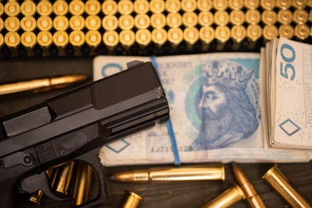 A gun and ammunition lie next to a file of banknotes during a business transaction.の写真素材