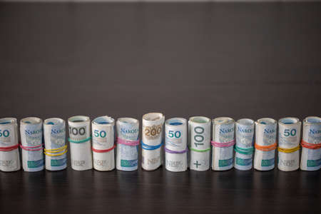 Banknotes rolled and tied together with a rubber band placed on a table.の写真素材