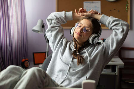A relaxed teenager listens to music on wireless headphones.の写真素材