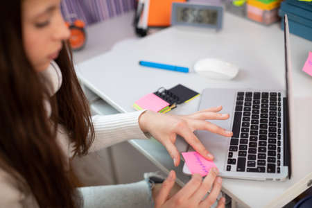 A teenager sticks a card on her laptop while learning English.の写真素材