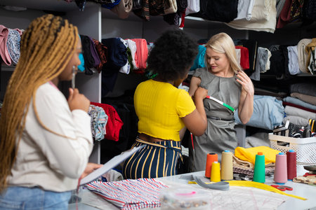 A dark-skinned seamstress measures the clients chest circumference.
