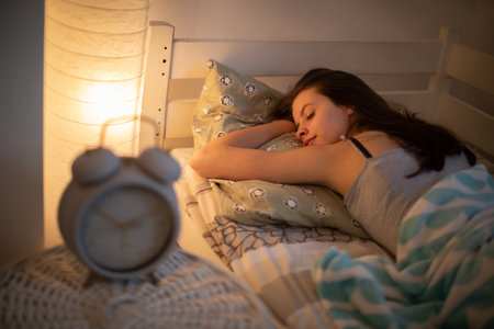 A woman with a slight smile sleeps on her stomach in her bed.の写真素材