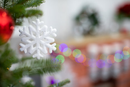 Snowflake-shaped bauble hangs on the branch of the Christmas tree.の写真素材