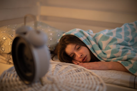 The drowsy aide looks reluctantly at her alarm clock.の写真素材