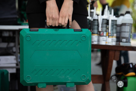 In the close-up frame, the girl holds a green tool case in her hands.の写真素材