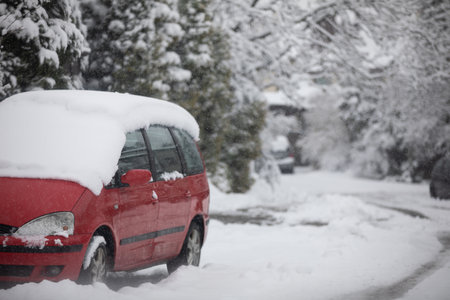 Red car parked on a very snowy estate roadの写真素材