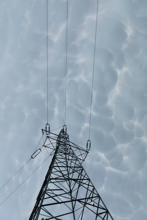A steel power transmission pole against a backdrop of storm clouds.