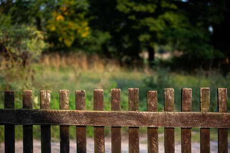 An old wooden village fence and in the background in a blur a green meadow.の写真素材