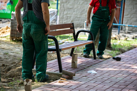 Physical workers set up a park bench at a designated spot in a city park.の写真素材