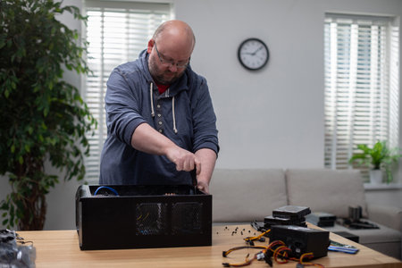 Man in glasses tightens screws on computer caseの写真素材