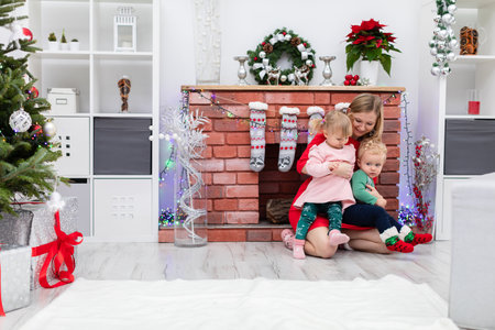 Loving mother holds her daughter and son on her lapの写真素材