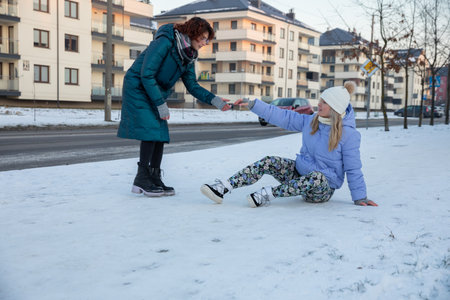 A passerby helps a woman get up who has stumbled in the snow.の写真素材