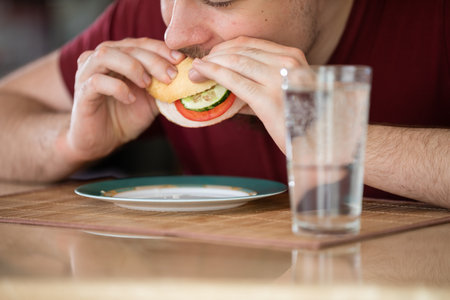 Close-up of a young man eating breakfast in the kitchen.の写真素材