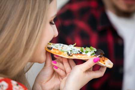 A hungry girl greedily eats a slice of pizza.の写真素材