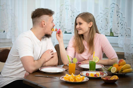 A woman feeds her husband at the table, serving him appetizers.の写真素材
