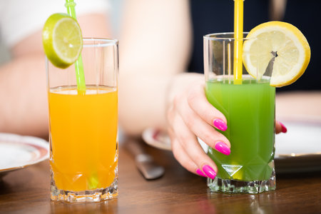Colorful fruit drinks with a straw on a wooden counter.の写真素材