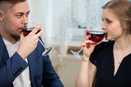 A man and a woman drink red wine at an elegant family gathering.