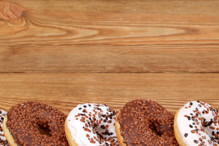 A Collection of Delicious Assorted Donuts Arranged Artistically on a Wooden Tableの写真素材