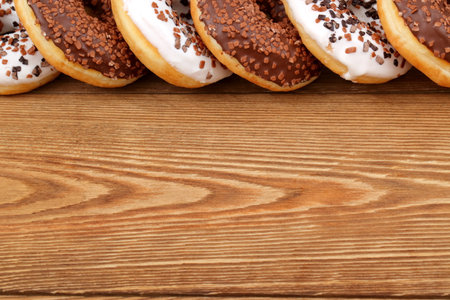 A Delicious and Attractive Assortment of Chocolate and Vanilla Donuts Resting on a Wooden Tableの写真素材