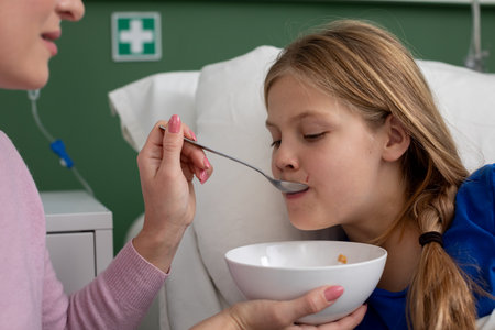 Caring Moment A Child Being Tenderly Fed While in a Hospital Room with Compassionate Supportの写真素材