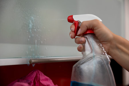Cleaning the glass surfaces with a spray bottle is an effective and essential taskの写真素材