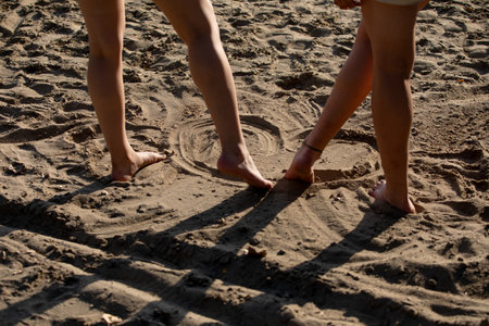 Two Bare Feet in Warm, Soft Sand Creating Beautiful Patterns at the Serene Beachの写真素材