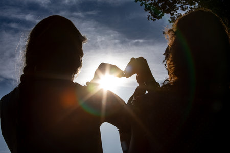 A HeartShaped Gesture Silhouette Elegantly Set Against the Beautiful Sunlight at Dusk,の写真素材