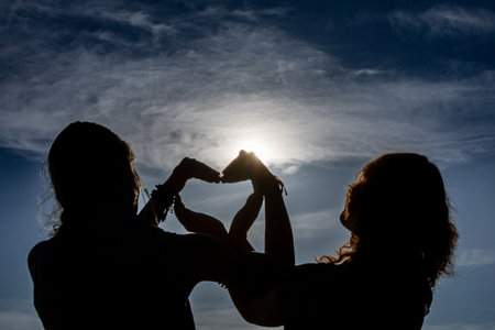 A Heart Gesture Silhouette perfectly captured against a beautiful Sunlight Backgroundの写真素材