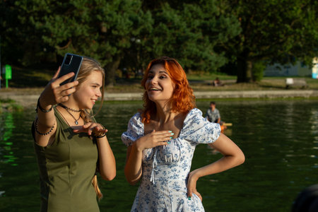 Joyful Friends Happily Taking a Fun Selfie Together by the Sparkling Waters Edge in Summerの写真素材