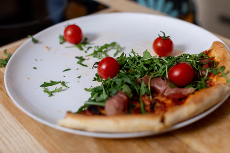 Deliciously Fresh Pizza Slice Topped with Cherry Tomatoes, Greens, and Aromatic Herbsの写真素材