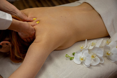 Enjoy a relaxing back massage with beautiful orchids for ultimate pampering experienceの写真素材