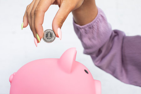 A Person Diligently and Carefully Inserting a Coin into a Piggy Bank for Future Savings Goalsの写真素材