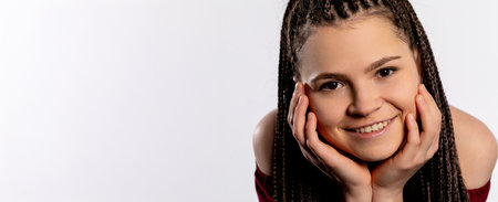 A Charming and Smiling Young Woman with Braided Hair on a Light and Bright Backgroundの写真素材