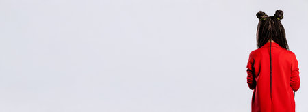 A Child Wearing a Bright Red Coat Stands Out Against a Minimalist Background Settingの写真素材