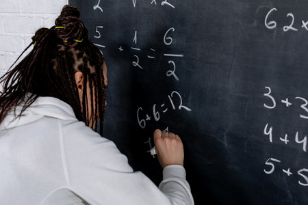 A person diligently solving complex math problems on a large blackboard in classの写真素材