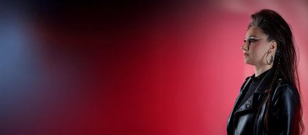 A Confident Woman in a Stylish Black Leather Jacket Against a Beautiful Gradient Backgroundの写真素材