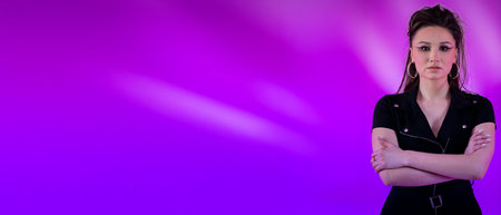 A Confident Woman in a Stylish Outfit Poses Gracefully Against a Captivating Purple Background