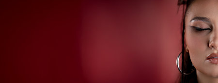 An Elegant Portrait Featuring Glamorous Makeup Set Against a Stunning Red Backgroundの写真素材