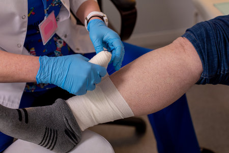 A skilled nurse is diligently bandaging the patients leg with utmost care and attention