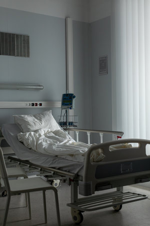 An empty hospital room with a bed and natural light, creating a serene space for recoveryの写真素材