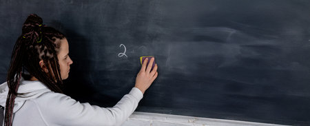 An Educator Diligently Writing on a Blackboard in a Collaborative Classroom Setting