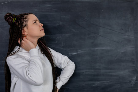 Contemplative Young Woman Deep in Thought Pondering Against a Chalkboard Background