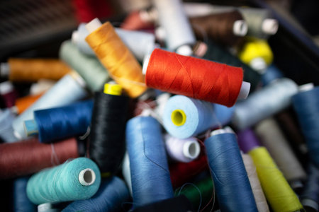A stunning variety of colorful spools of thread are beautifully piled together in one single placeの写真素材