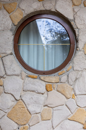 A beautifully crafted circular window integrated within a stunning stone wall design