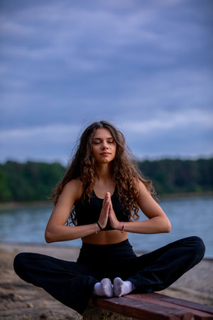 Enjoy a Serene Yoga Practice by the Water at Dusk, enveloped in natures beauty and tranquilityの写真素材