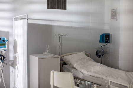 A hospital room furnished with an empty bed and various essential medical equipment presentの写真素材