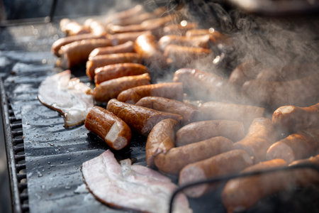 Enjoy the culinary delight of grilling succulent sausages and crispy bacon on a hot barbecue grill
